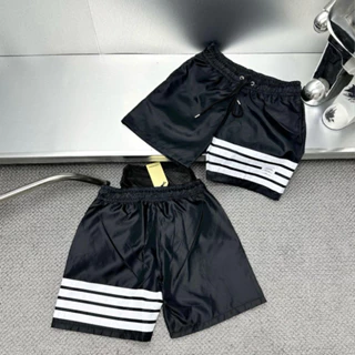 Quần short gió nam Thom Browne đen in 4 sọc trắng thêu logo chữ cạp chun dây thắt lót lưới cao cấp QS65P L76